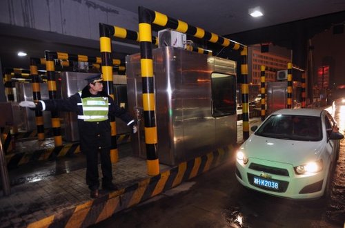 2月9日凌晨，在通往京港澳高速的长沙星沙收费站，工作人员指挥一辆汽车驶过。