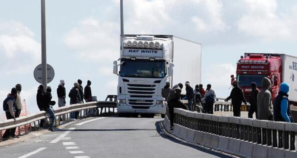 法国加莱的高速路旁，聚集着大批非法移民，他们守候在高速路旁，趁机爬上前往英吉利海峡货轮港口的大卡车，偷渡到英国。
